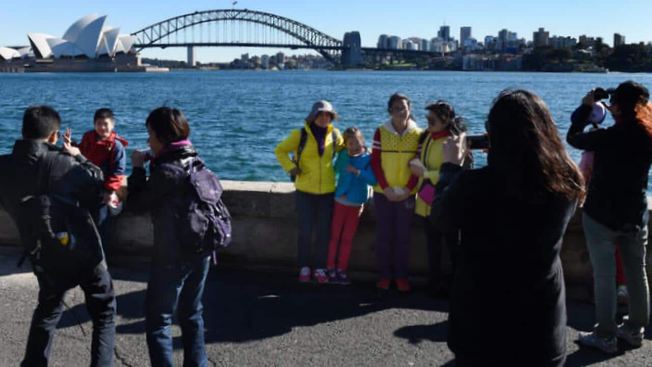 Chinese tourists take in the sites of the Sydney Harbour Bridge and the Sydney Opera House from Mrs Macquarie's Chair in Sydney, Tuesday, July 14, 2015. (AAP Image/Dean Lewins) NO ARCHIVING (AAP)