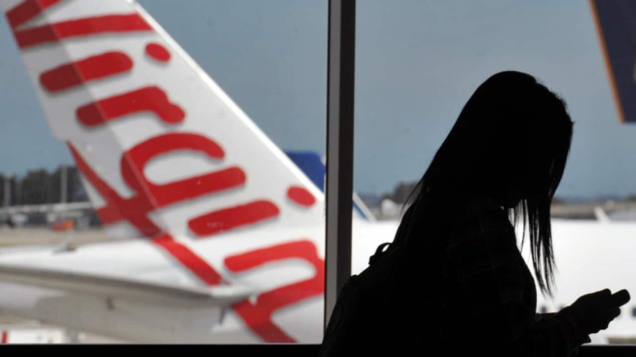 A passenger passes a Virgin Australia aircraft in Sydney