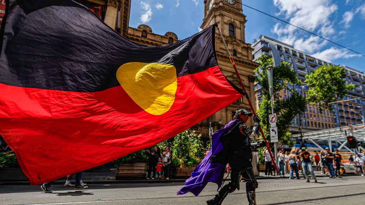 A man carrying an Aboriginal flag on a city street