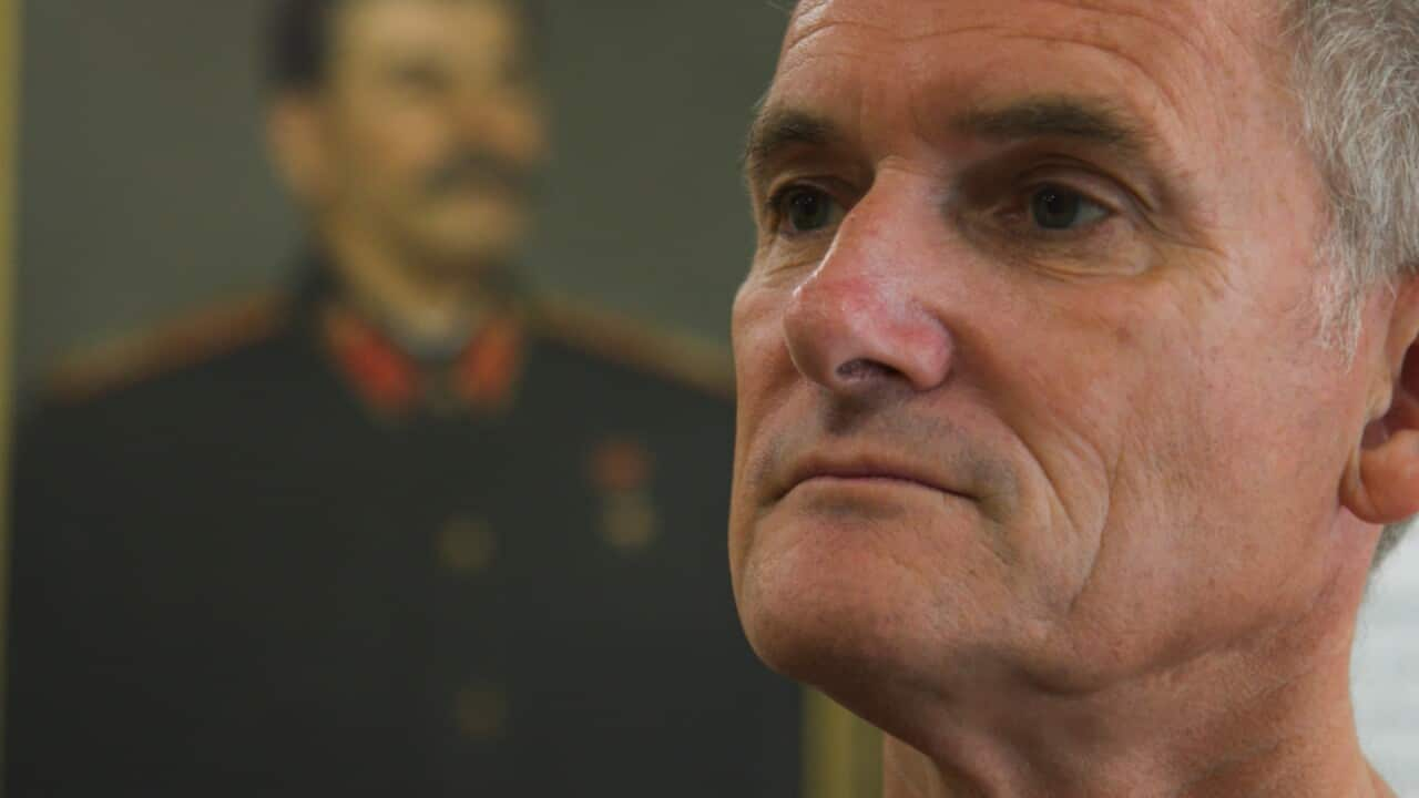 A man's face against the backdrop of Joseph Stalin's portrait 