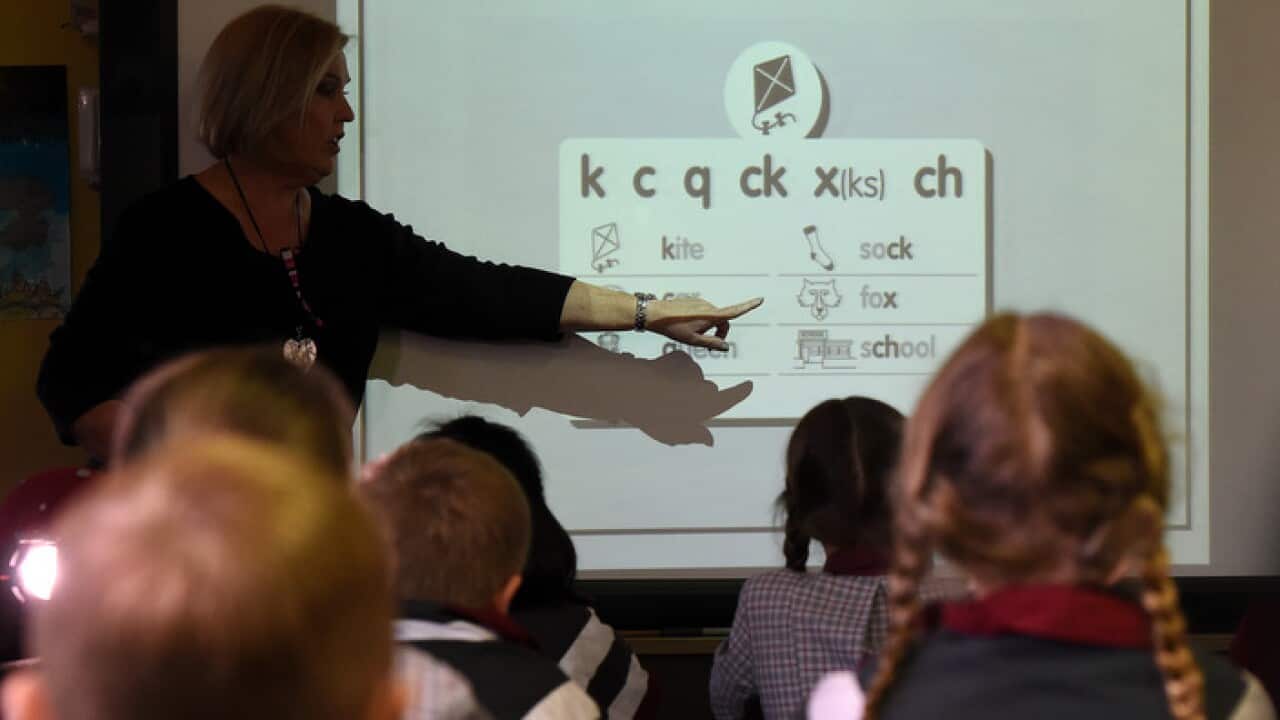 A teacher points at a board during a lesson at State School in Brisbane.
