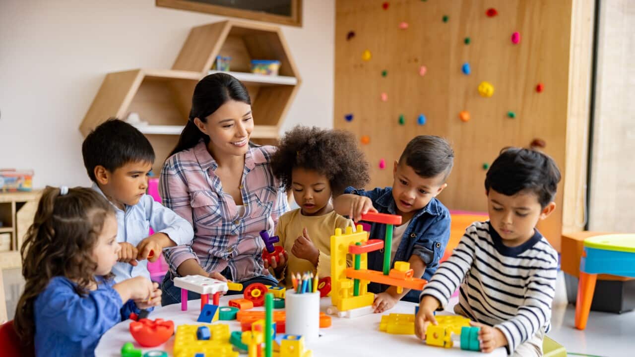 Teacher with a group of elementary students playing with toy blocks