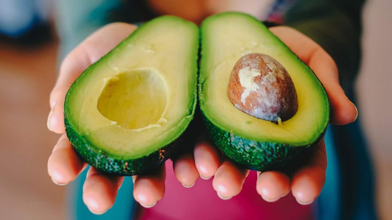 Woman holding cut avocado