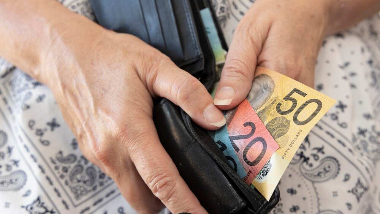 Hands holding a black wallet containing some Australian banknotes.