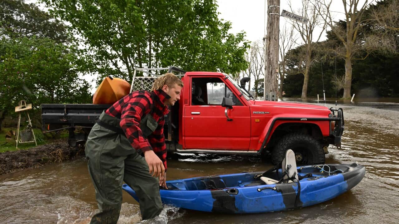 Riley Davis is seen pushing a kayak through flood water in Tinamba in eastern Victoria, Thursday, October 5, 2023. Victoria's river systems are flooding after days of heavy rain, especially in the east where residents have been told to leave due to increased threat. (AAP Image/James Ross) NO ARCHIVING