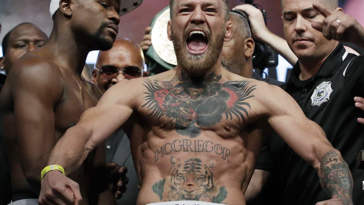 Conor McGregor, center, stands next to Floyd Mayweather Jr.