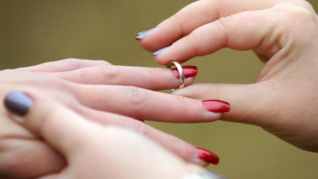 A woman places a wedding ring on her partners finger