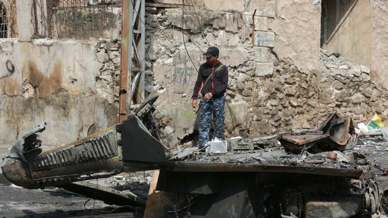An Iraqi policemen takes up position at a street in Mosul