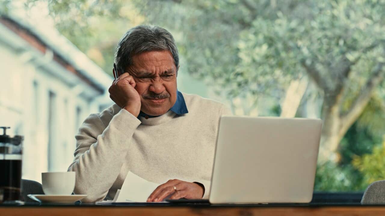 Shot of a senior man using a laptop and going through paperwork at home