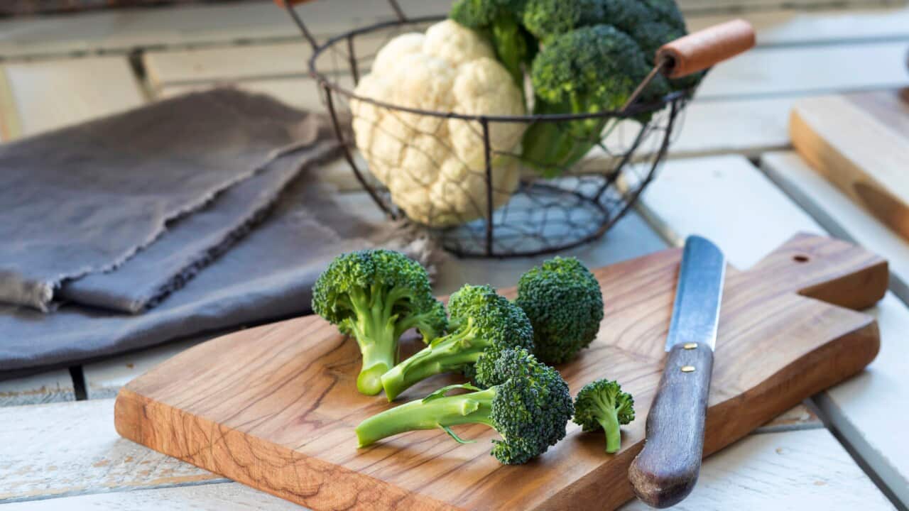 Broccoli florets and kitchen knife on wooden board