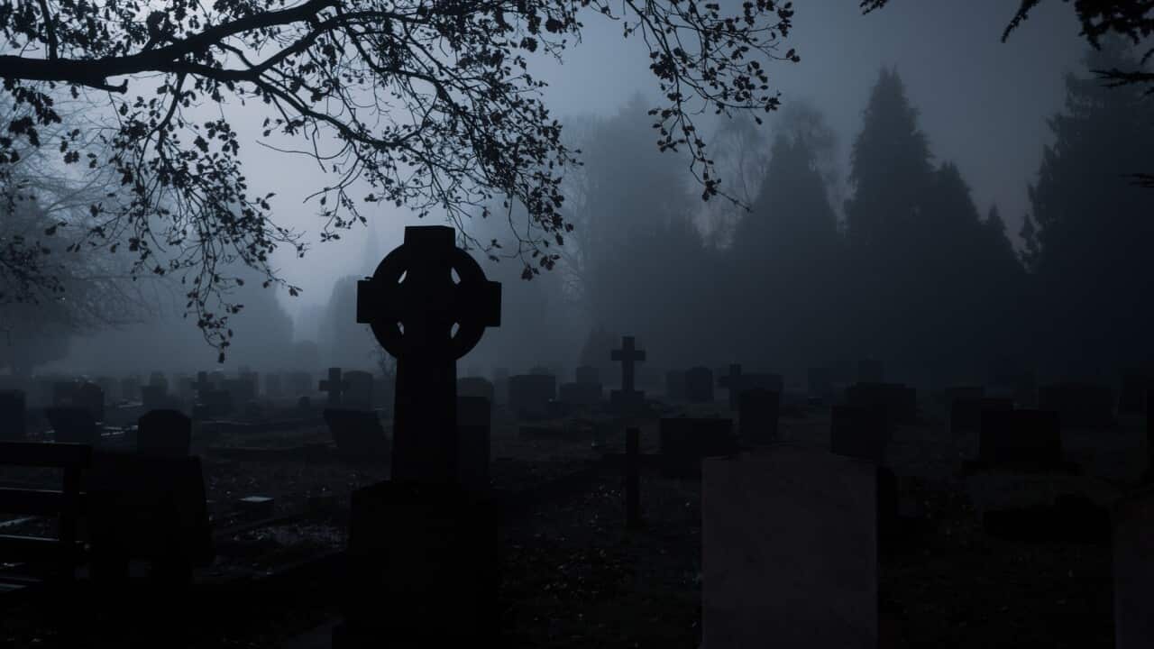 Spooky gravestones in a churchyard on a foggy winters mysterious night.