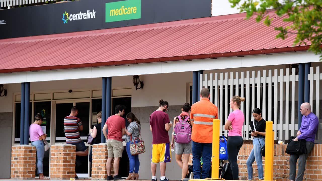 People are seen in a long queue outside a Centrelink office in Brisbane, 24 March 2020.