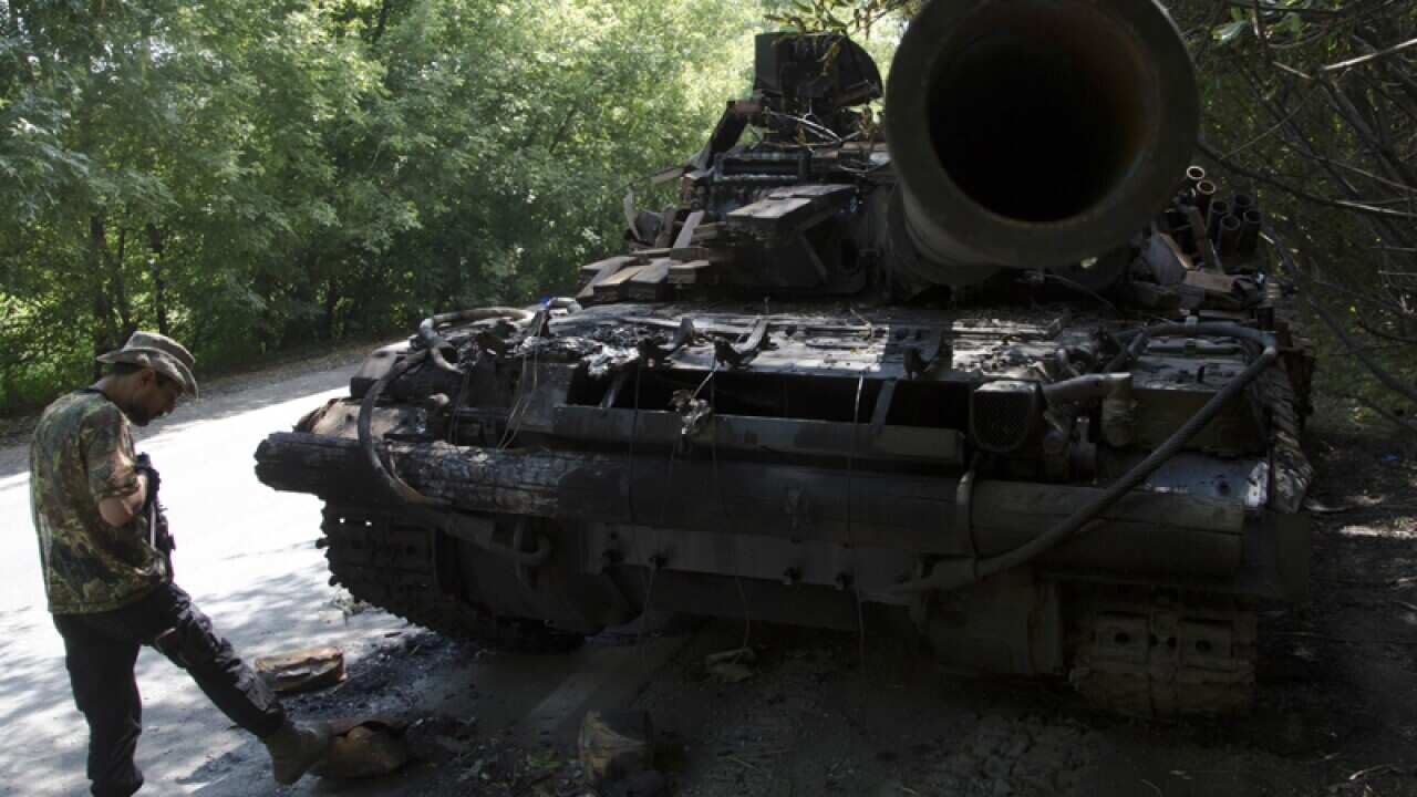 Pro-Russian fighters stands next to destroyed tank in Donetsk.
