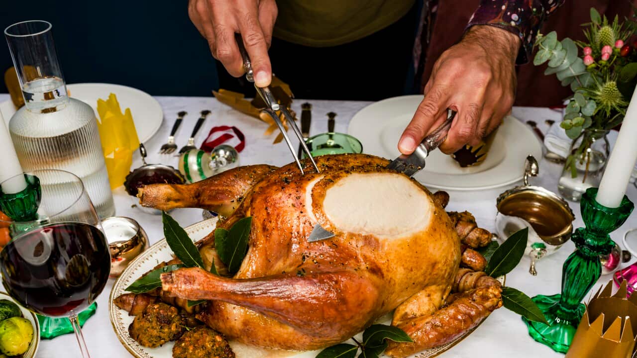 Man carving roasted turkey at traditional Christmas table