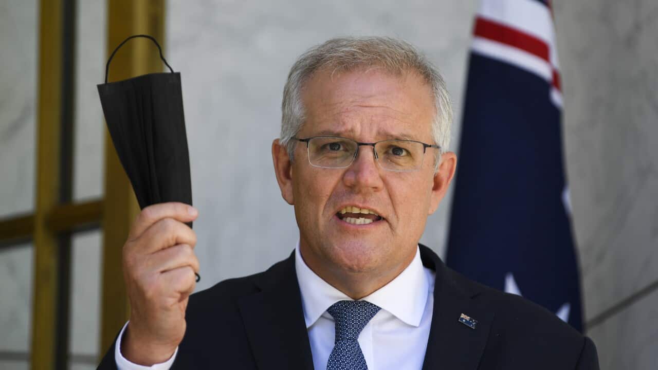 Australian Prime Minister Scott Morrison holds up a face mask as he speaks during a press conference following a national cabinet meeting.