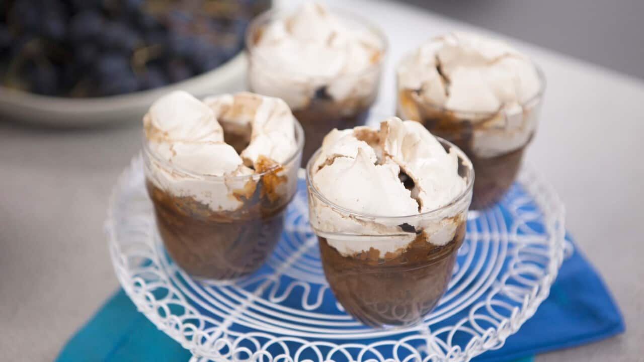 Four individual puddings, topped with meringue, sit on a white decorative rack.