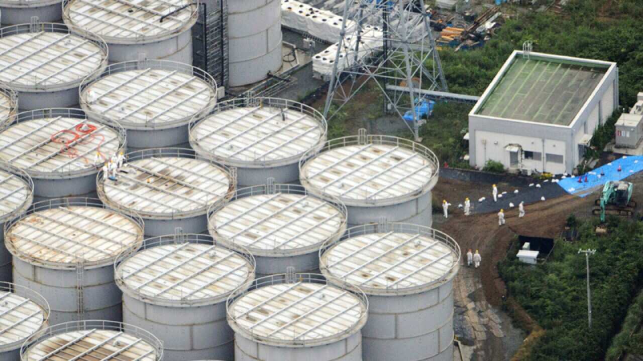 Workers stand on storage tanks at the Fukushima nuclear plant