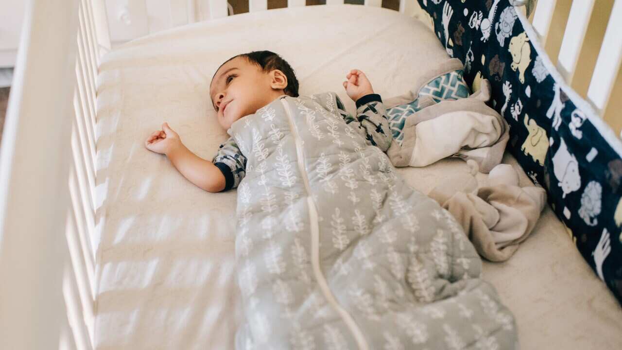 Baby boy lying awake in crib, high angle view