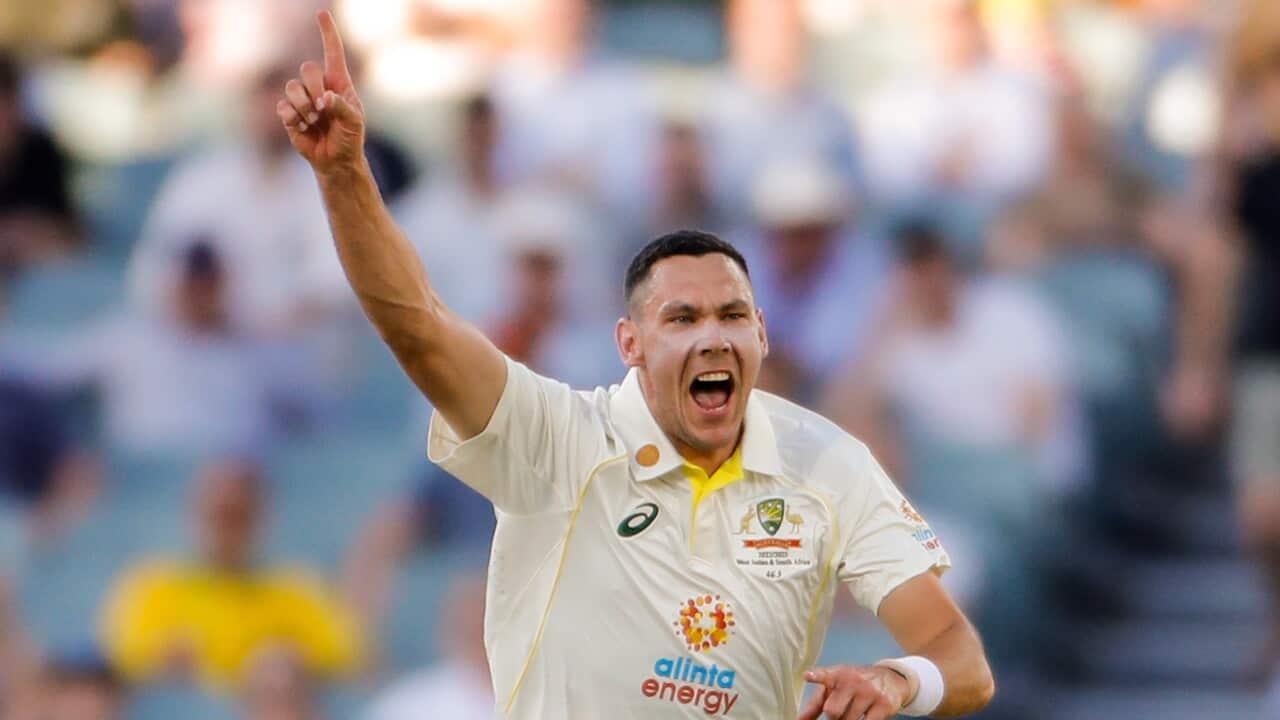 scott boland holds his hand in the air and runs in a stadium