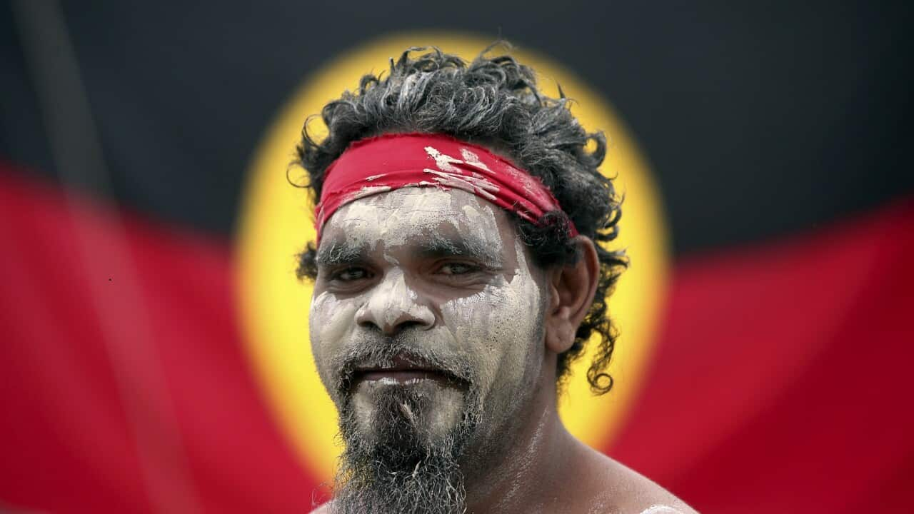 Musician Stedman Sailor in front of the Aboriginal Flag , about to take part in a smoking ceremony as part of Australia Day in Sydney, 2018 (AAP) 