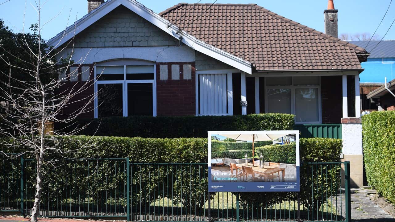 A house with a for sale sign outside it.