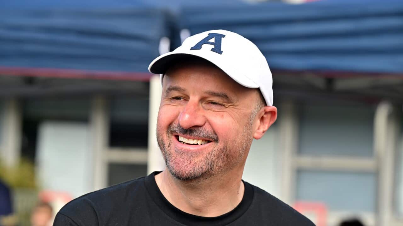 A man wearing a hat and a t-shirt smiles.