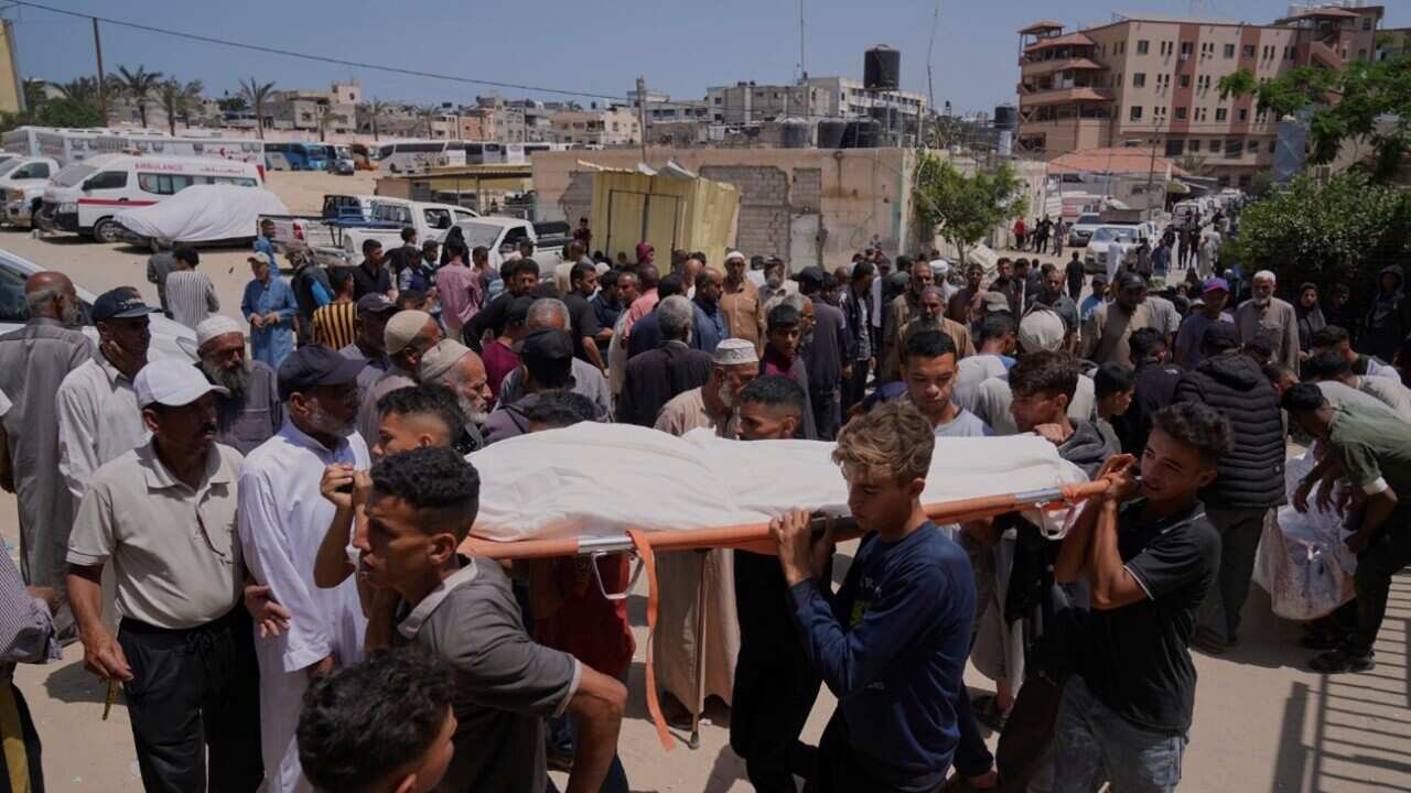 Palestinians carry the body of a person who was killed while heading to a Gaza aid hub (AAP).jpg