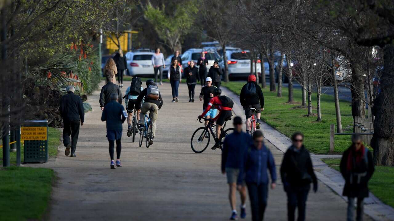 People walking, jogging, and riding bikes along a dirt path.