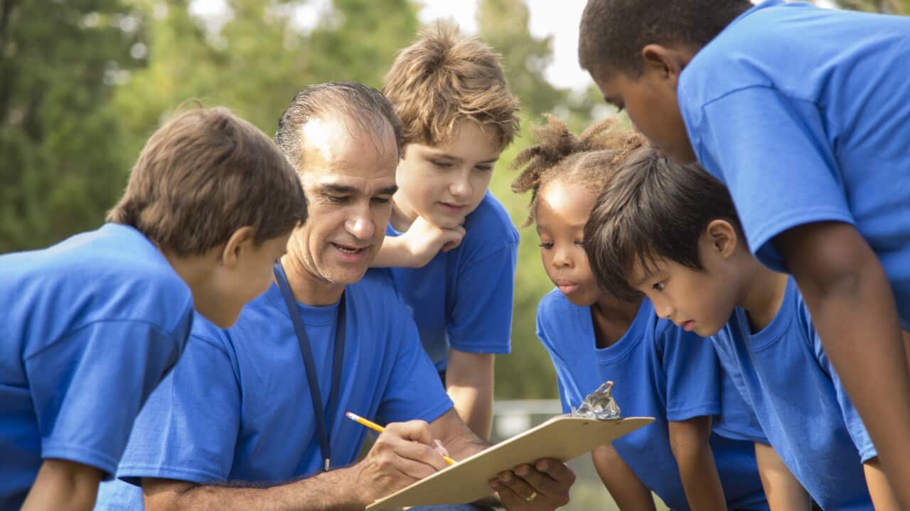 Soccer team coach explains next play to his children's team.