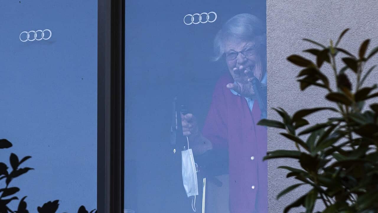 A resident at the Arcare Aged Care facility in Maidstone reacts to media from her window, in Melbourne, Monday, May 31, 2021. (AAP Image/Daniel Pockett) NO ARCHIVING