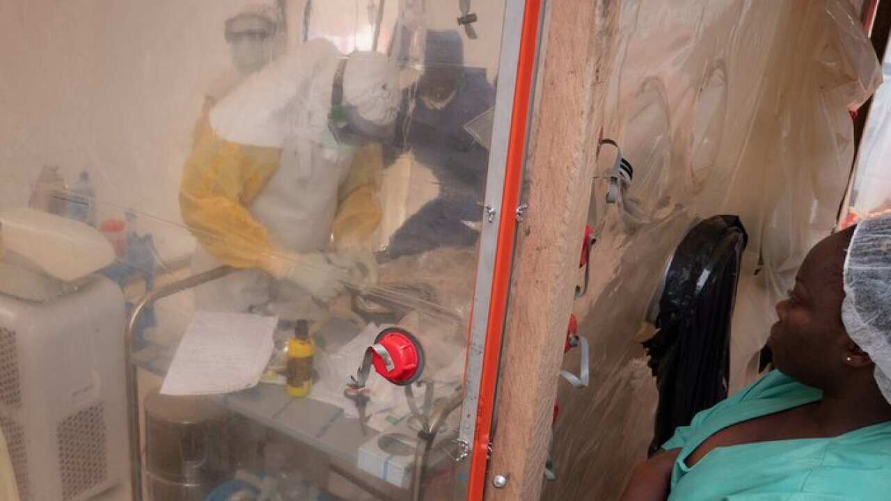 An Ebola health care worker examines a one week old infant in an isolation tent at an Ebola treatment center in Beni, North Kivu, Democratic Republic of the Congo.