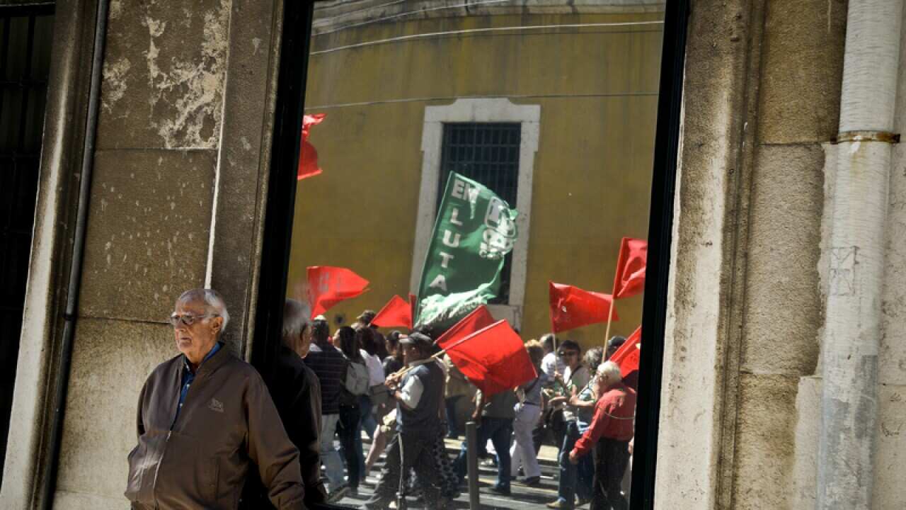 A man watches protesters pass during a demonstration in Lisbon
