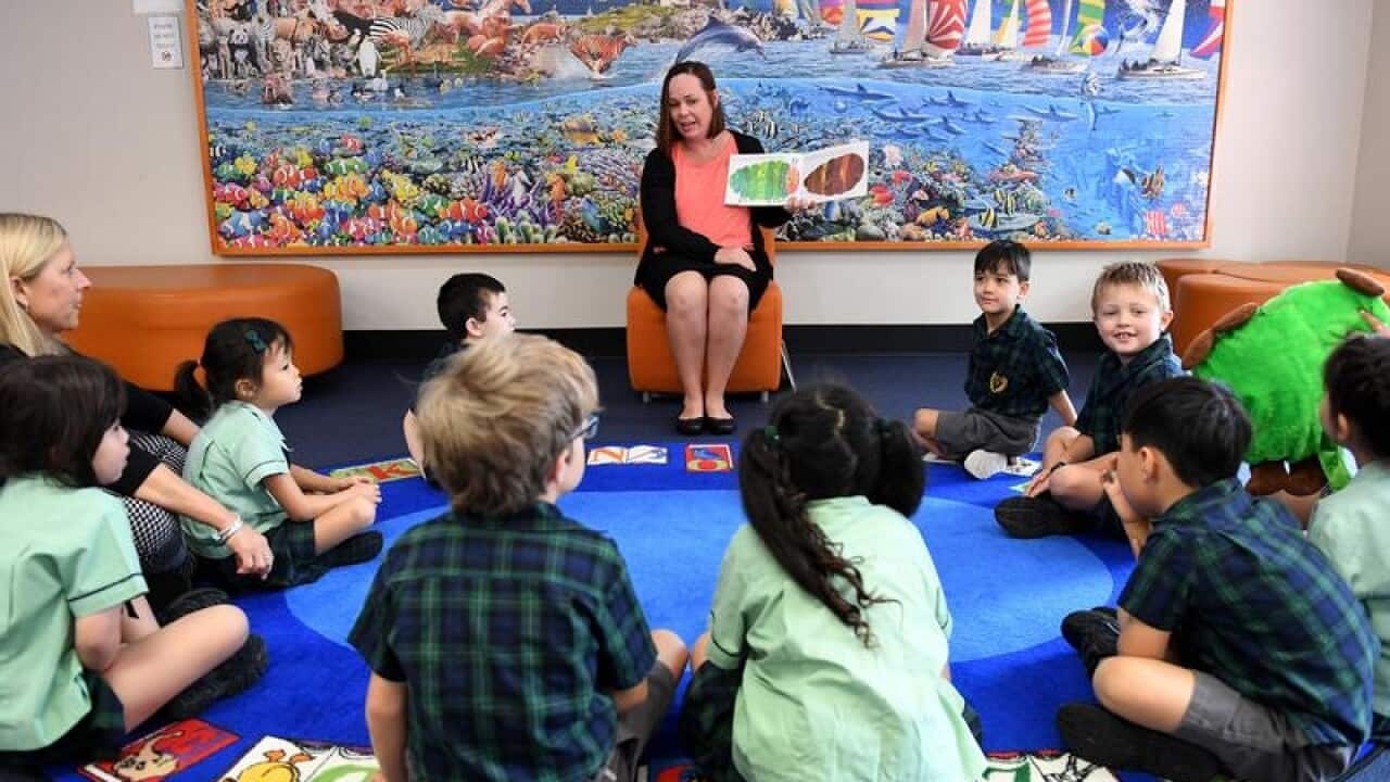 A teacher reads a story to young students