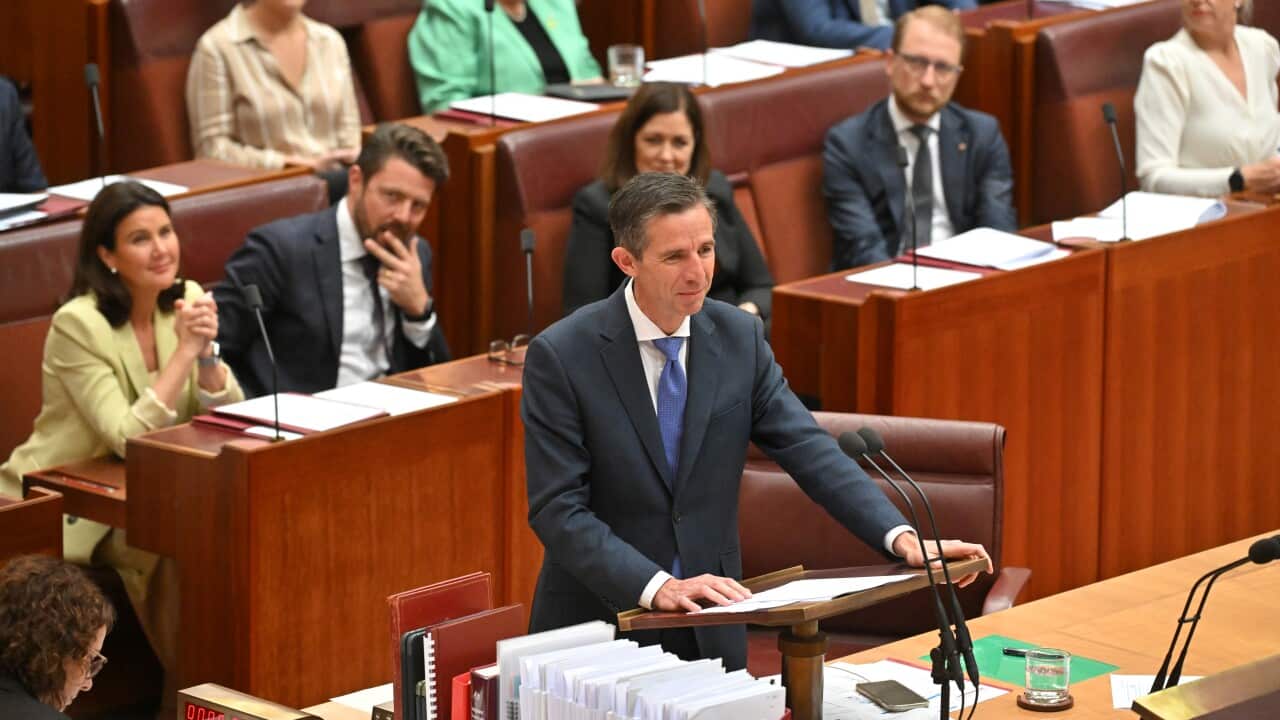 A man in a suit speaks in the Senate chamber.
