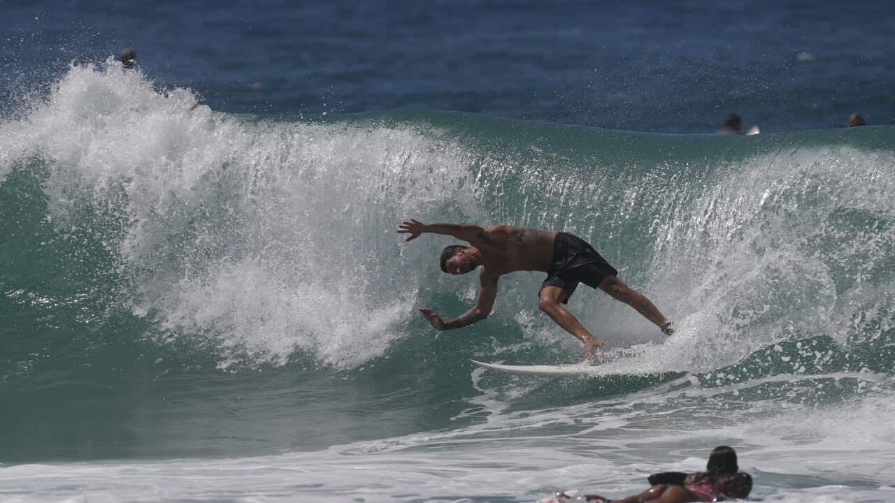 A surfer falls into the water at a beach on the Gold Coast