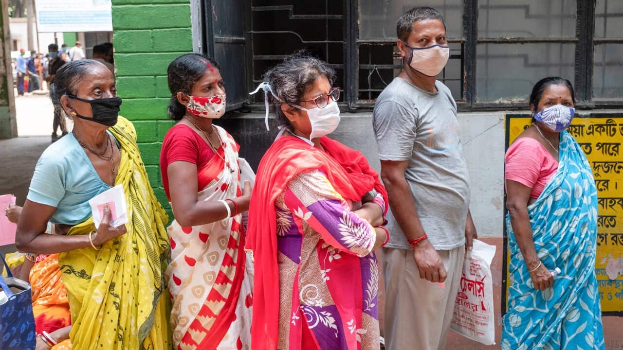 People stand in a long queue with no social distance before getting a Covid19 test in a testing kiosk at a rural hospital in India.