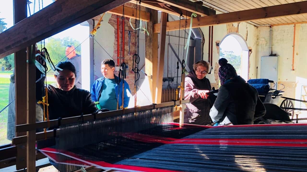 A Karen woman weaving Karen traditional longyi on a loom machine.