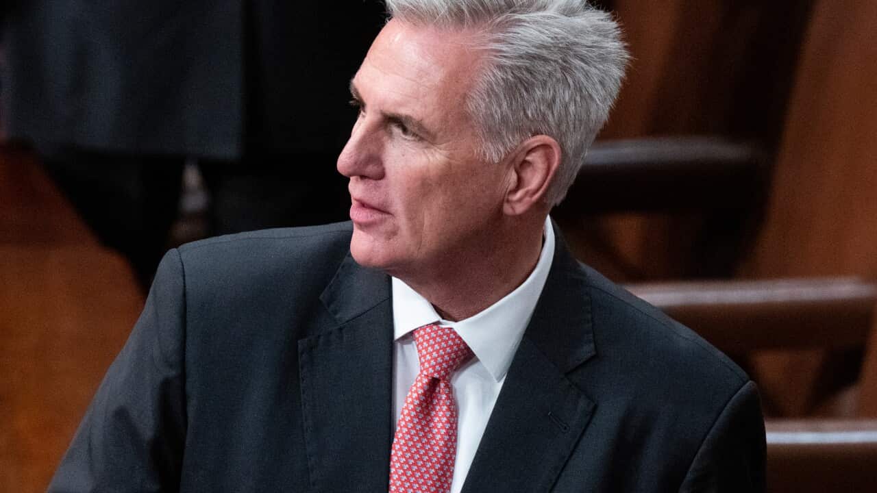 A man wearing a suit and tie standing in the US House of Representatives.