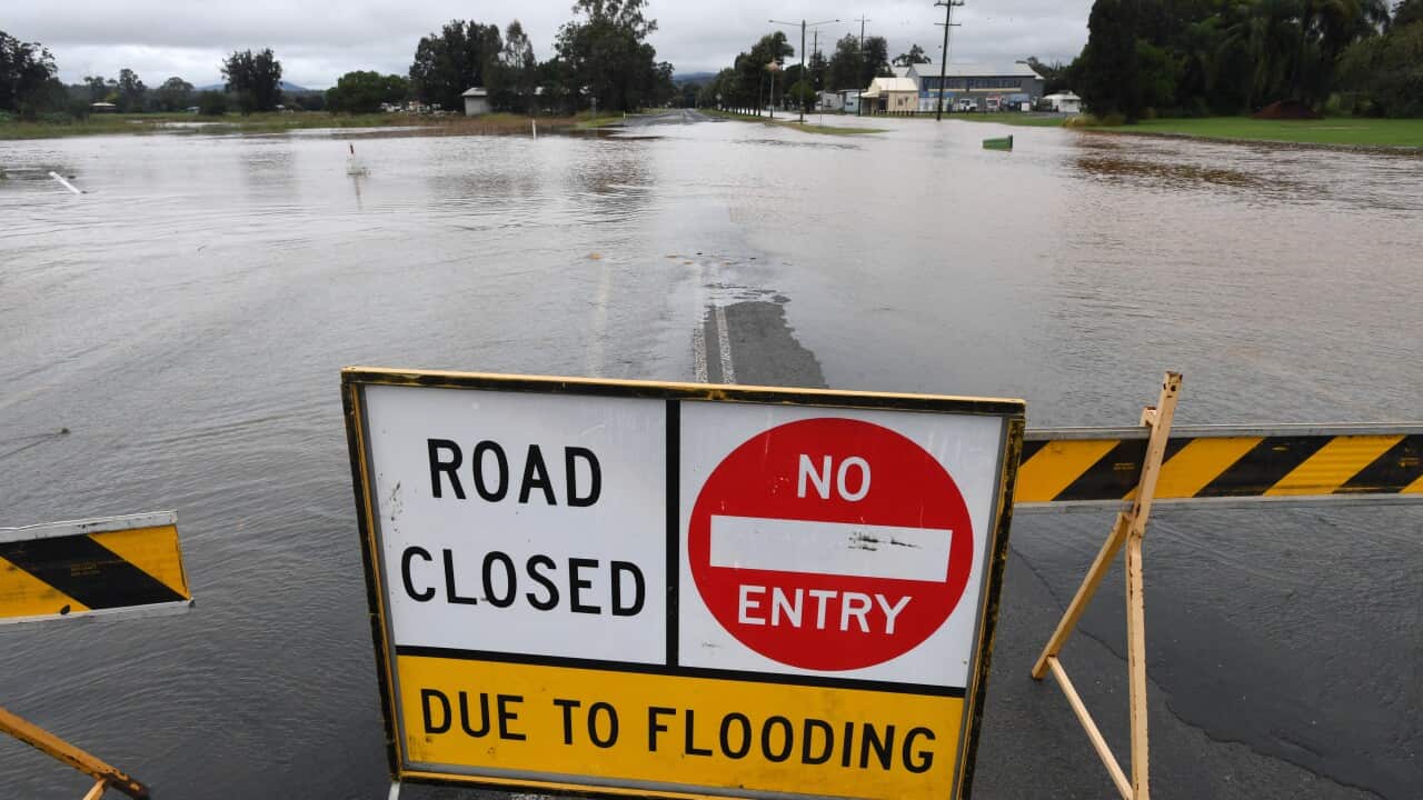 A sign in front of a flooded road reads: road closed, no entry due to flooding