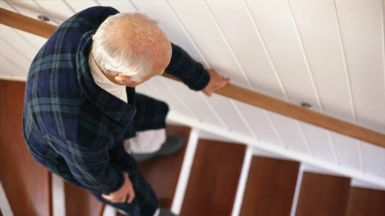 An elderly man carefully descends a staircase