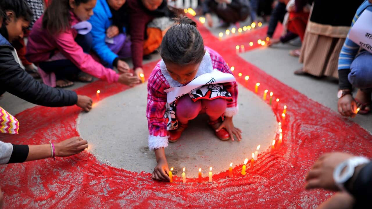 A little girl lit candles around the symbol of RED AIDS during Eve of the World AIDS Day celebrated in Kathmandu, Nepal.