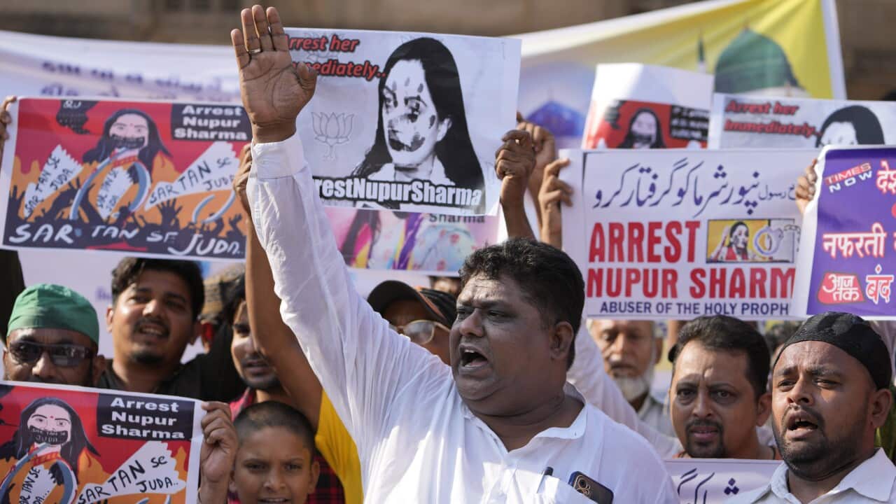 A man raises his right hand while several people stand behind him during a protest.