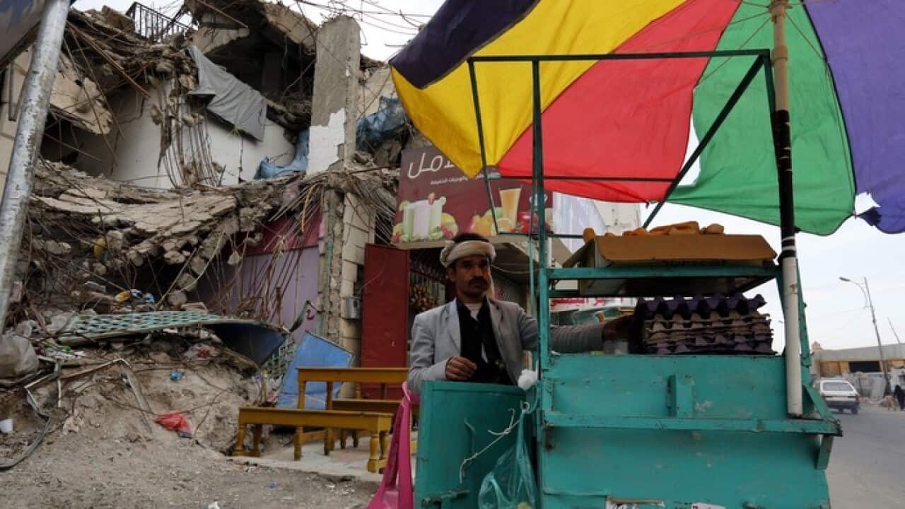 A street vendor works near a building destroyed during Yemen’s civil war (AAP)