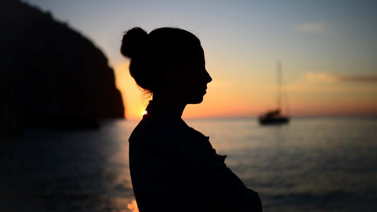 Silhouette of a contemplative young woman enjoying a beautiful sunset