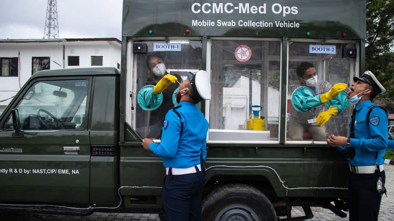 Health officials take a throat swab from from traffic policemen for COVID-19 PCR testing while sitting inside a mobile swab collection vehicle in Kathmandu.