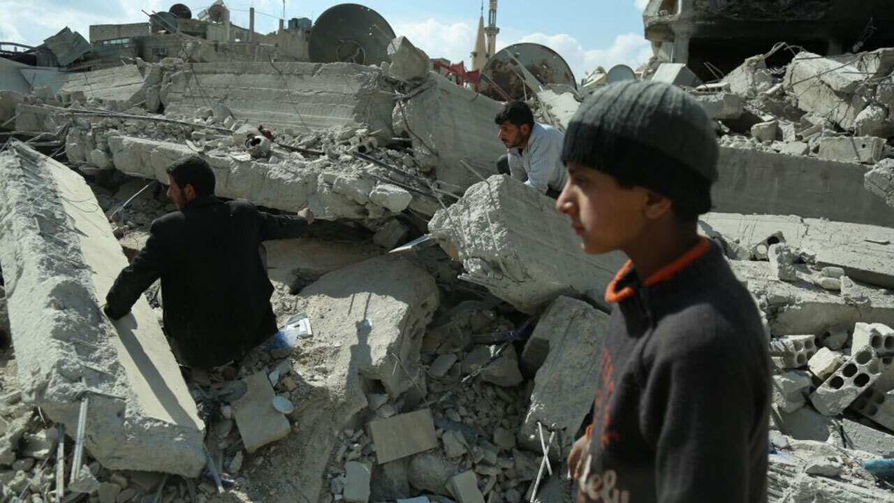 Syrian civilians search for survivors amid the rubble of buildings which were destroyed earlier in regime air strikes, in the rebel-held besieged town of Douma.