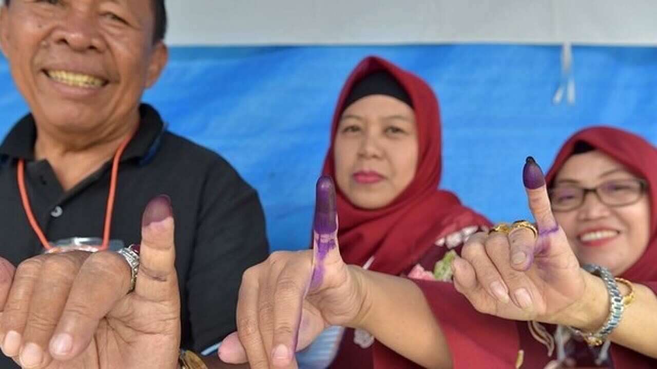 Indonesian people show their inked fingers after casting their ballots during regional elections in Tangerang, Banten on June 27, 2018.