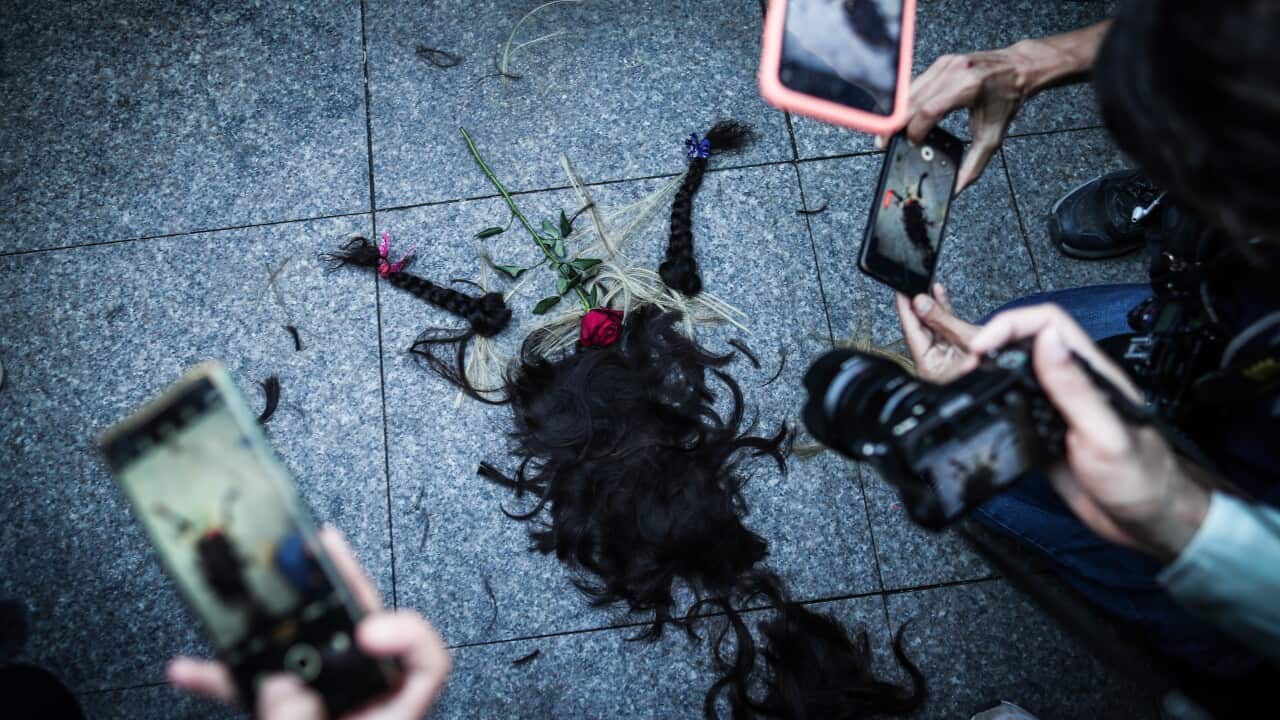 People take photos of a pile of hair cut by Iranian women during a protest following the death of Iranian Mahsa Amini (AAP)