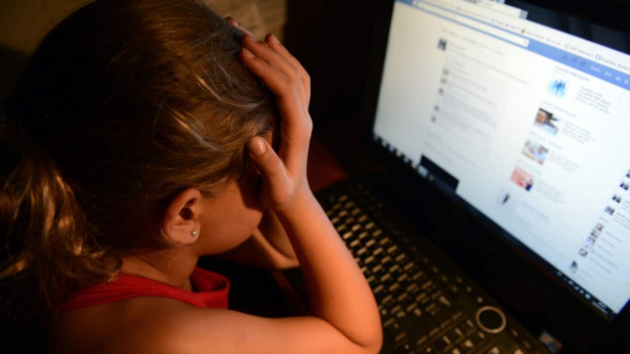 An upset young girl in front of a computer.