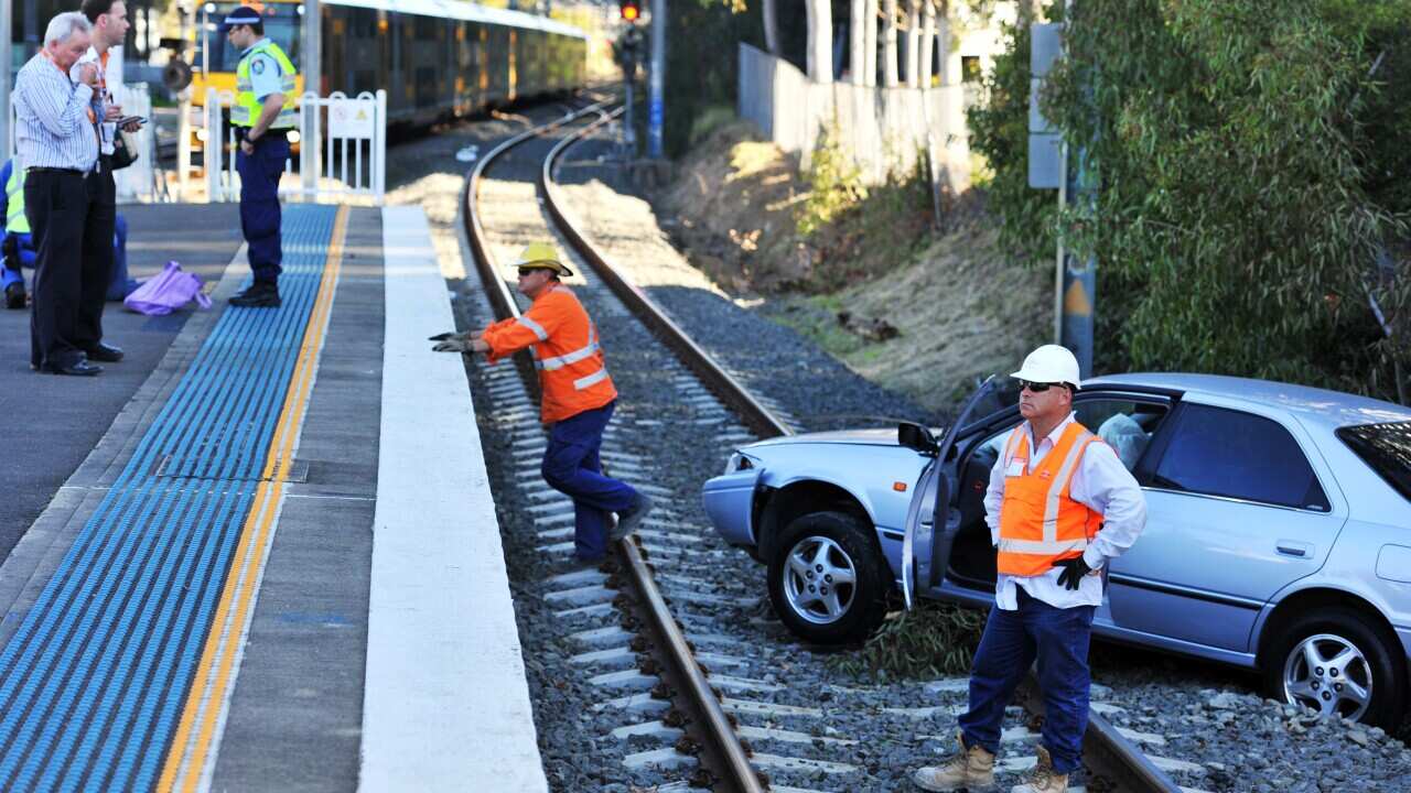A car lies on the train tracks after driving over an embankment in Rhodes, Thursday, Sept. 11, 2014. A woman believed to be the driver walked away from the scene aided by the help of New South Wales emergency personnel. (AAP Image/Sam Mooy) NO ARCHIVING